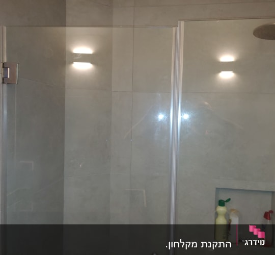 מקלחת עם ראש מקלחת ומדף עם בקבוקי סבון